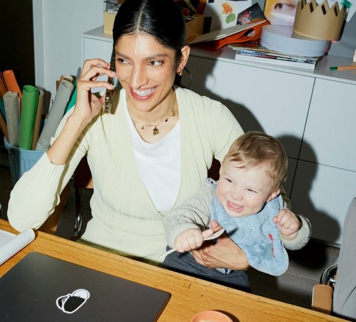 Une consultante au telephone chez elle, son enfant dans les bras.